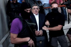 553572-nikos-michaloliakos-entoure-de-policiers-masques-a-la-sortie-des-locaux-de-la-police-le-28-septembre.jpg